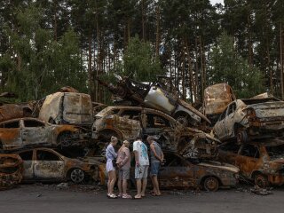 Люди біля своєї зруйнованої автівки
