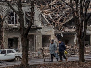Люди на тлі зруйнованого міста / фото: CNN