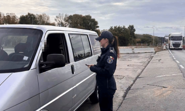 Пограничница проверяет документы у водителя на границе
