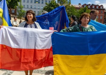 Українські біженці тримають прапор Польщі та України