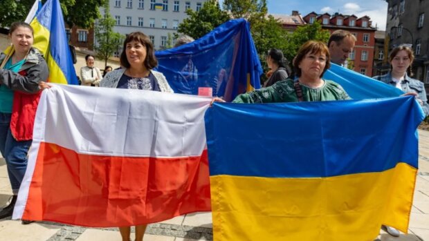 Украинские беженцы держат флаг Польши и Украины