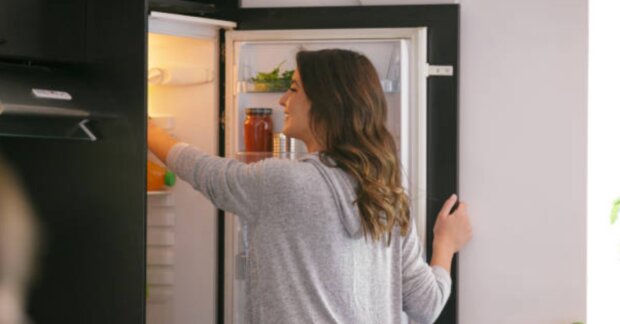 Женщина, которая лезет в холодильник