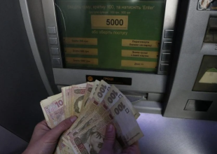 Людина знімає готівку в банкоматі. Фото: bbc