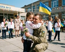 військовий батько обіймає доньку останній дзвоник школа