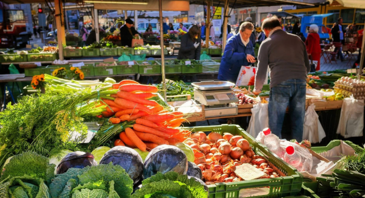 Женщина покупает овощи на рынке