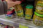 Людина дістає горошок з полиці