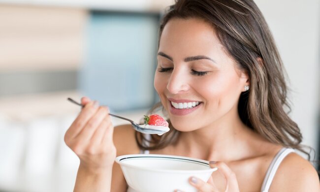 Женщина ест йогурт