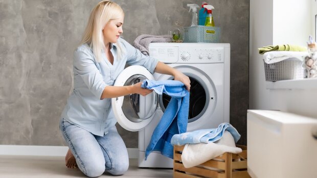 Жінка дістає речі з пральної машинки
