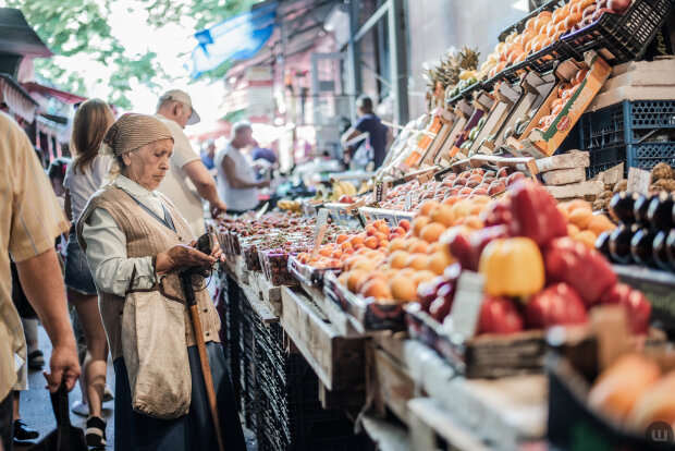 Пенсионерка покупает фрукты и овощи