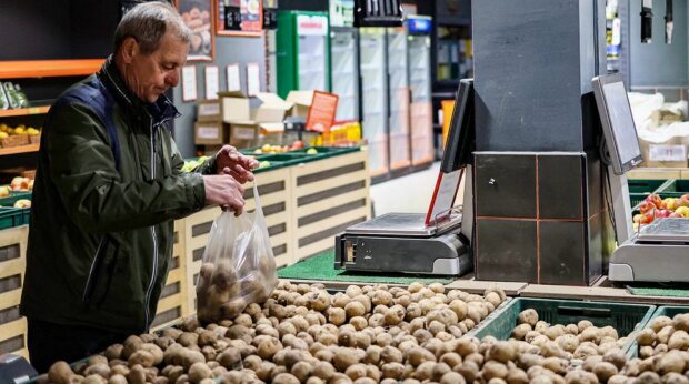 Человек, выбирающий картофель в магазине