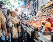 Пенсионерка покупает фрукты и овощи