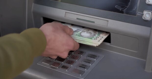 Человек получает деньги из банкомата