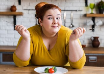 Жінка з зайвою вагою і продукти на тарілці