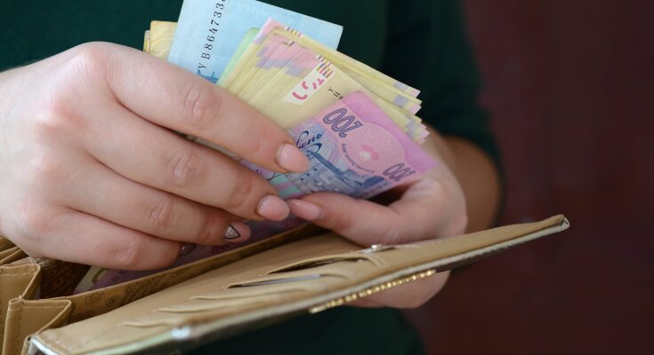 Жінка, яка кладе гроші в гаманець