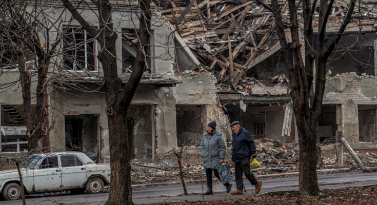 Люди на фоне разрушенного города / фото: CNN