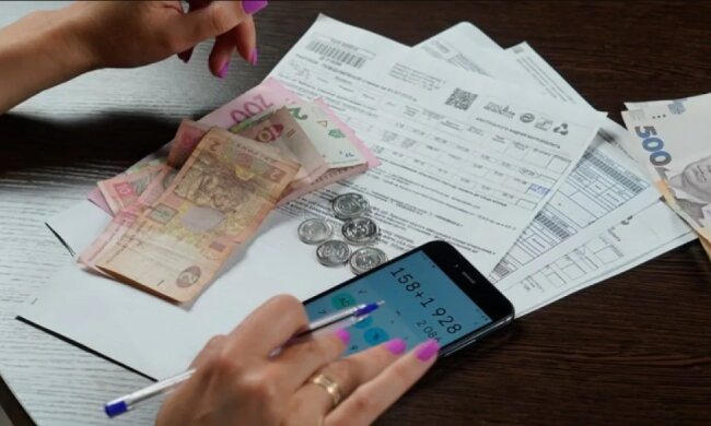 Жінка оплачує рахунки за комуналку