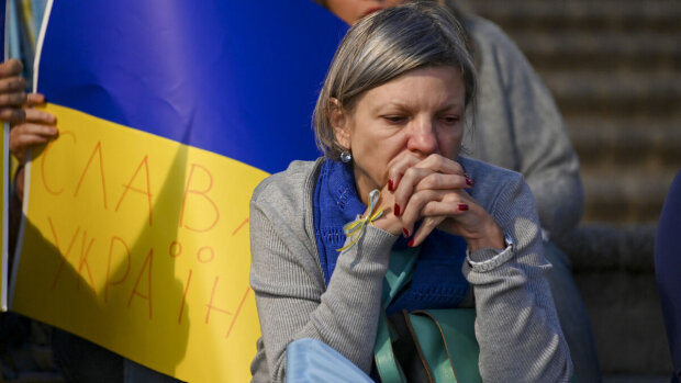 Жінка, яка сидить на фоні українського прапору