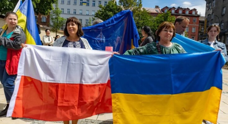 Украинские беженцы держат флаг Польши и Украины