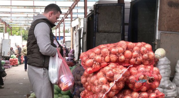 Чоловік на ринку біля цибулі