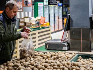 Человек, выбирающий картофель в магазине