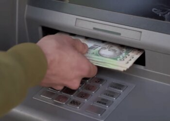 Человек получает деньги из банкомата