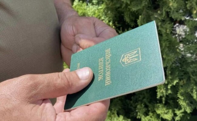 Человек, держащий в руках военный билет