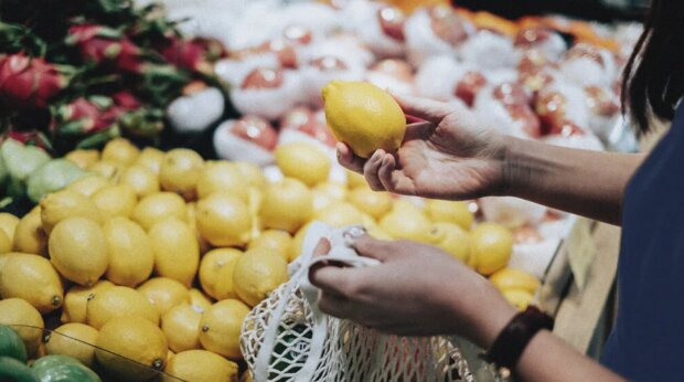 Женщина, выбирающая лимон в магазине