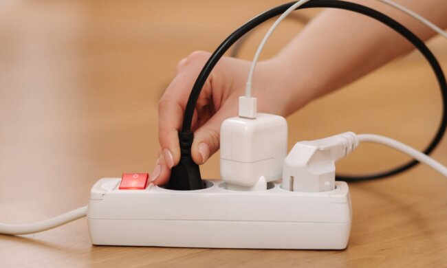 Людина витягую провід з подовжувача. Фото: freepik