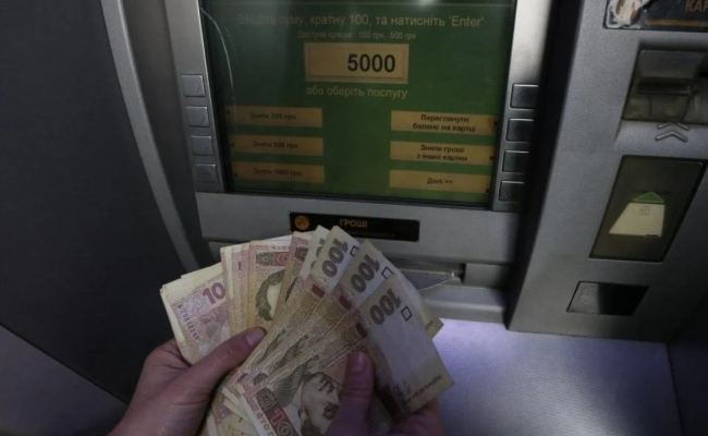 Человек снимает наличные в банкомате. Фото: bbc