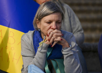 Жінка, яка сидить на фоні українського прапору