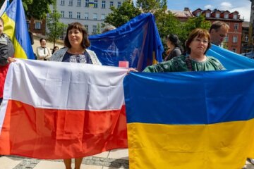 Українські біженці тримають прапор Польщі та України