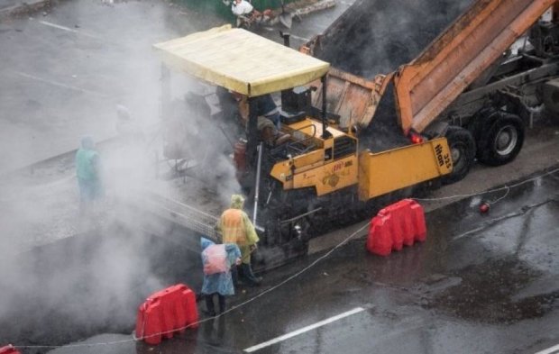 Киевские коммунальщики бросились ремонтировать дороги под дождем 