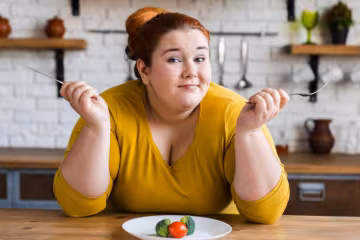 Жінка з зайвою вагою і продукти на тарілці