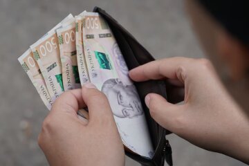 Человек, держащий кошелек с деньгами