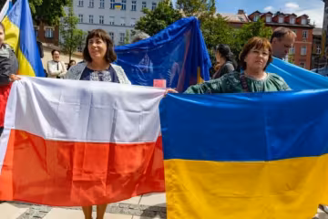Украинские беженцы держат флаг Польши и Украины