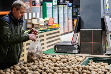 Человек, выбирающий картофель в магазине