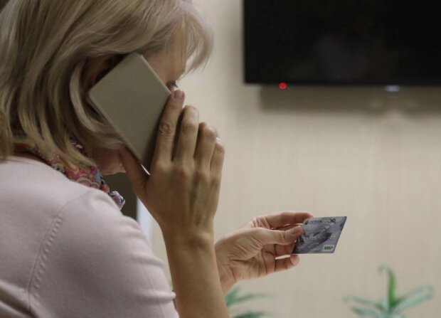 Женщина разговаривает по телефону и держит карту в руках.