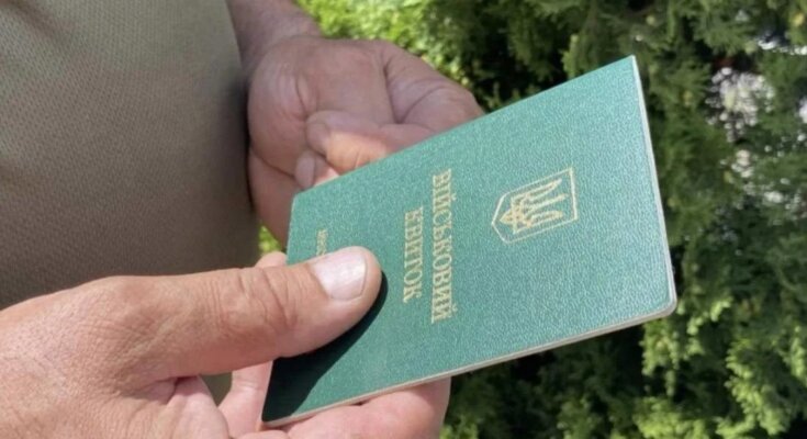 Человек, держащий в руках военный билет