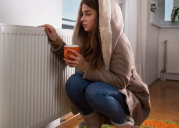 Девушка сидит возле батареи