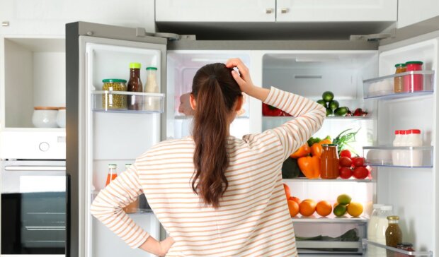 Женщина, стоящая у холодильника