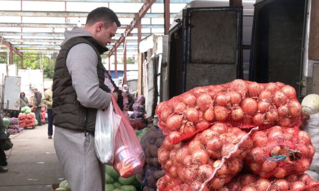 Чоловік на ринку біля цибулі