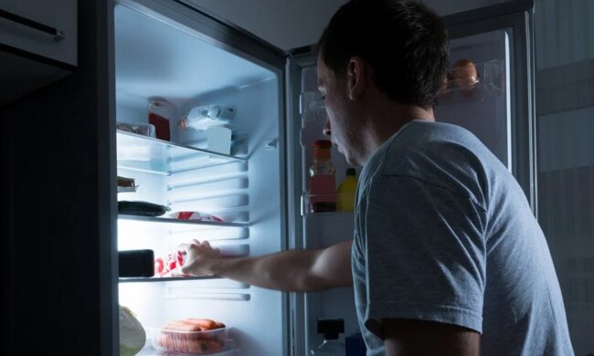 Чоловік, який лізе до холодильника